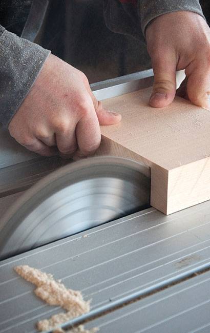Hands using a table saw for handyman woodworking.